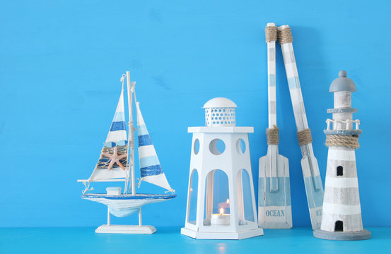 nautical concept with white decorative lantern, lighthous, wooden oars and boat oars over blue background.