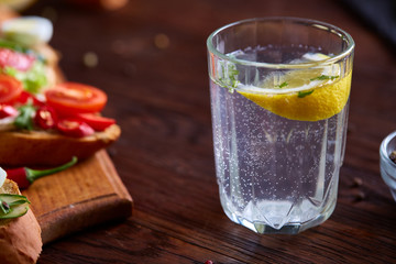 Glass of water with fresh lemon on wooden background, close-up, selective focus