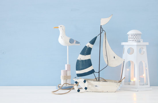 nautical concept image with white decorative seagull bird, boat and lighthouse lantern over light blue background.