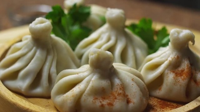 Close up of spinning plate of delicious khinkali dumplings seasoned with chili pepper