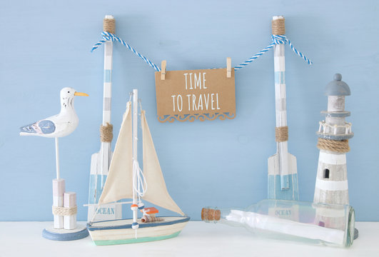 nautical concept with hanging note on a string next to lighthouse, boat, letter in the bottle and seagull over blue background.