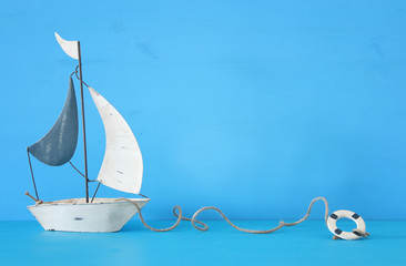 nautical concept with white decorative sail boat over blue wooden table and background.
