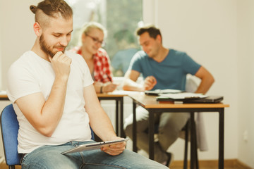 Fototapeta premium Student boy with tablet in front of her classmates