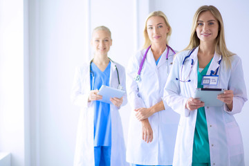 Fototapeta premium Portrait of three confident female doctors standing with arms crossed at the medical office.