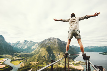 Man raised hands balancing at the edge in Norway mountains Travel lifestyle risk concept active...