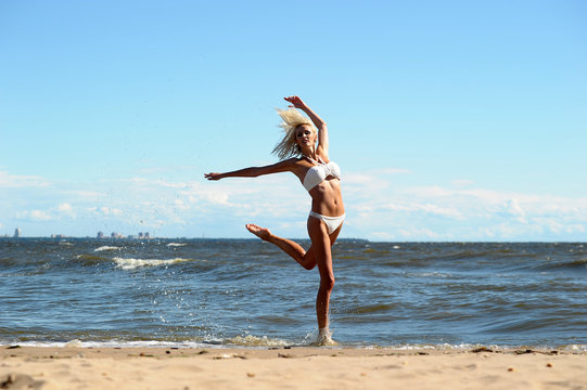 beautiful blonde in a swimsuit is jumping near the sea