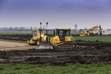 Excavators and bulldozers preparing the ground for the construction of a factory