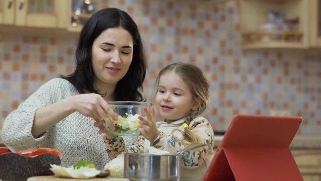 Cute little girl helps mother at the kitchen