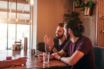 Group of mixed race young men talking in lounge bar. Multiracial friends having fun in cafe
