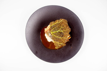 Sturgeon, savoy cabbage, mushrooms broth, mashed potato with butter on a plate on a white background