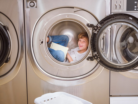 Boy reading book in laundry machine