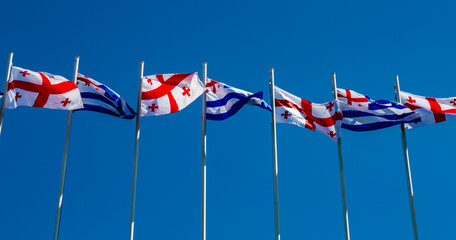 National flags of Georgia and Adjara against a blue sky on a sunny day
