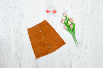 Brown skirt with buttons, pink sunglaasses and bouquet of tulips. Fashionable concept