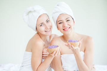 Two happy young girls show salt Treatment therapy spa with towel on her head