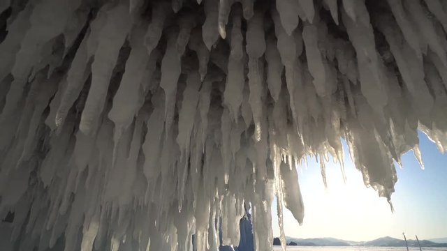 Huge sharp transparent ice icicles unique splashes brilliant. Sunny dawn in cave rock. Winter frost day blue sky. Research discovery. Wild untouched innocent. Russia Baikal lake landscape Gimbal Dolly