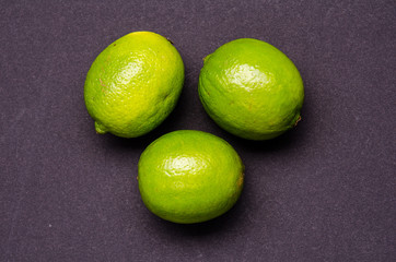 three green limes on a grey background