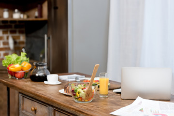 close-up shot of freelancer workplace at kitchen with food on table and laptop