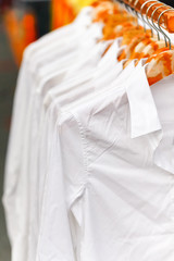 Crease white shirts hanging on rack in a row, Selective focus