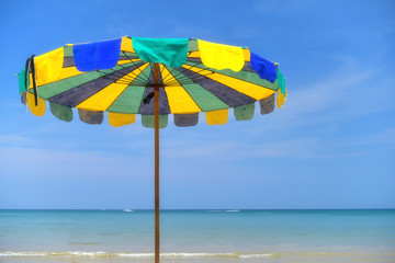 Obraz premium Colourful umbrella beach on tropical beach background, summer time concept.