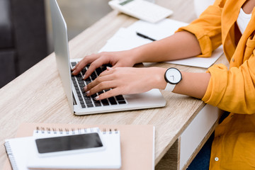 cropped shot of woman using laptop at office