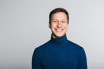 Casual guy with a warm smile over white grey background.