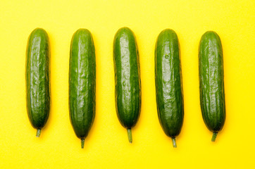 five symmetrically positioned small cucumbers on a yellow background