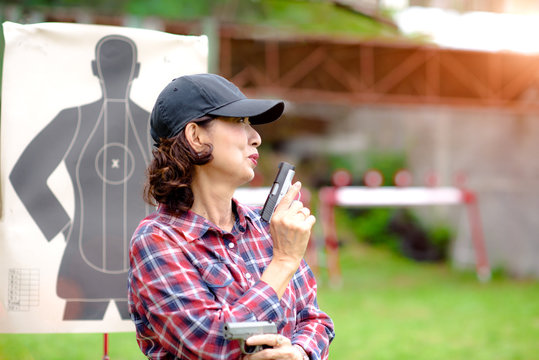 old woman enjoying gun shooting while hand holding a Short magazine gun in practice of arm and weapon martial art for woman