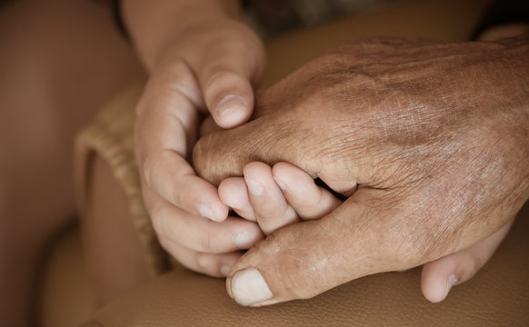 Hands of little Asian kids holding poor elderly grandfather man hands wrinkled skin with feeling take care of Love. World Kindness Day concept and Adult day care center, Relationship of Family concept
