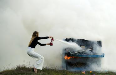 Sexy woman with long hair at piano on fire, Halloween. Music style and art. Fire and smoke on...