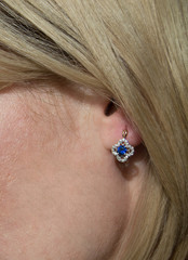 Golden earring with dark blue gem - sapphire and few diamonds in model's ear