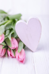 Pink tulips and pink heart on a wooden background. Happy Valentine's Day. Free space