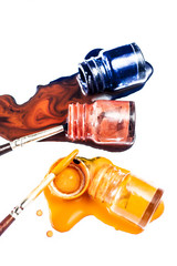 3 colored bottle of poster color fallen on white surface i.e. orange, red and dark blue colored.