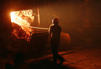 Plant for the production of steel. An electric melting furnace. Factory worker takes a sample for...