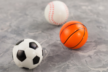 Three new soft rubber soccer and basketball and baseball balls on old worn cement