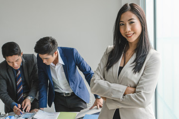 Beautiful asian businesswoman / manager standing folded arm on colleagues background in office / workplace.