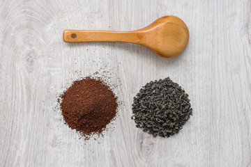 Instant granulated coffee ,dry leaves of black tea and wooden spoon on a wooden background