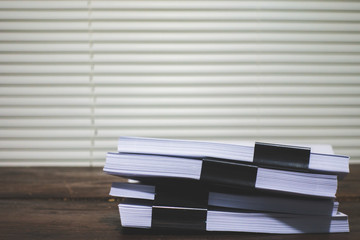 Stack of business report paper file on wooden table.