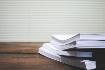 Stack of business report paper file on wooden table.