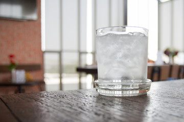 A glass of ice in the water on the wooden table ,Cool off in the summer.