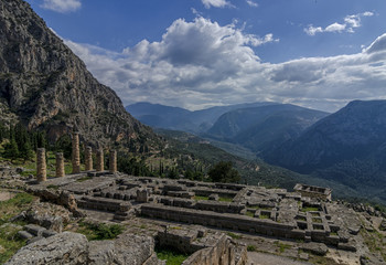 Fototapeta na wymiar Delphi, Phocis / Greece: The Temple of Apollo at the archaeological site of Delphi with a beautiful panoramic view on a sunny day with blue cloudy sky