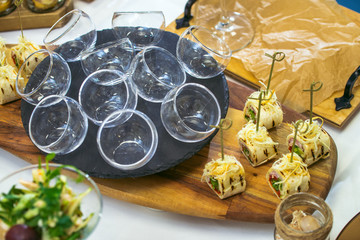 Beautiful decorated catering banquet table with different food snacks and appetizers. Canape rolls in small pans on wood