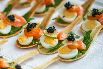 Delicates, appetizer filling with red fish, quail egg, black caviar and lime. Catering service.