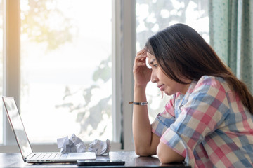 Young asian lady feeling tired and stressed. woman working with laptop computer and paperwork...
