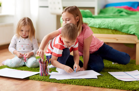 childhood, leisure and people concept - happy kids drawing and making crafts at home