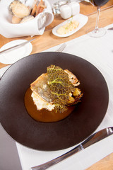 Sturgeon, savoy cabbage, mushrooms broth, mashed potato with butter served in a restaurant