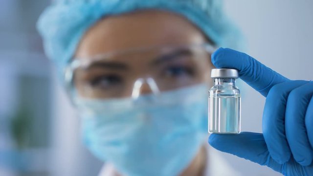 Female scientist holding ampoule in hand, new medication developing, vaccination