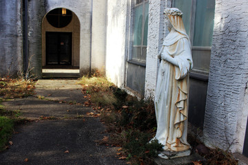 Fototapeta na wymiar Virgin Mary statue outside of old abandoned rural church