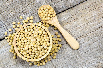 Top view of Soybean raw in wooden bowl and wooden spoon on wooden background.