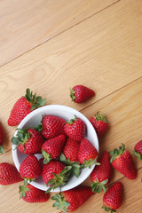 Fresh strawberries in a bowl on wooden background