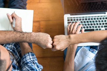 Business start up partners teamwork. Top view of Designer and programmer doing fists bump after work is done and build project corperate successful together at office.